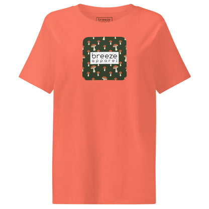 Orange t-shirt with square graphic of mushrooms set on a green background overlaid with a white rectangle in which 'breeze apparel' is in black.