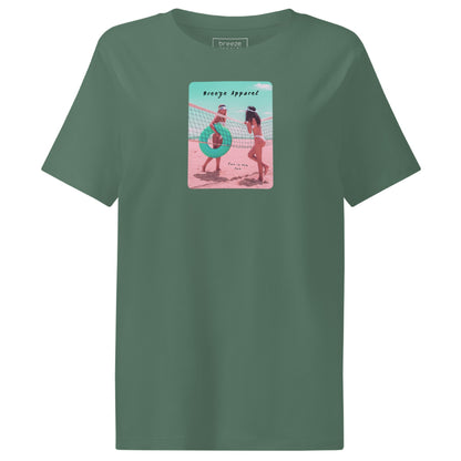 Green t-shirt with an image of two women in bikinis on the beach, standing by a volleyball net, one holding a swim ring and smiling, the other leaning on the net, with inscription in black of 'breeze apparel' towards the top of the image, and 'fun in the sun' in black on the ground between the women. 