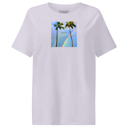 Lavender t-shirt with a graphic of palm trees, rainbow, and a clear blue sky in the background. A small, black 'breeze apparel' logo is between the trees.