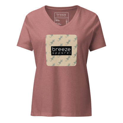 Mauve t-shirt with square over chest that contains pattern of green geckos set on beige background, overlaid with black, rectangular logo with white lettering.